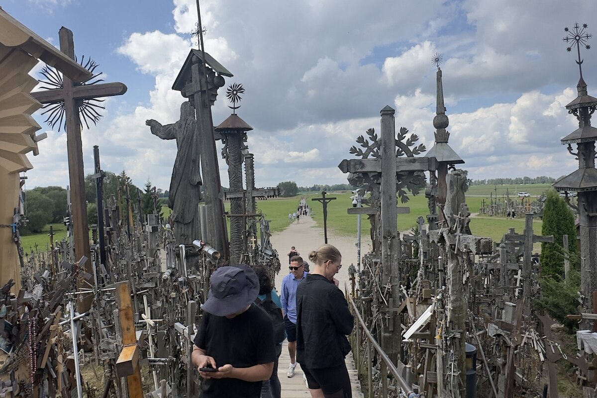 Collina delle Croci, Lituania, la passerella d’accesso con la statua di Gesù pellegrino e le croci intagliate a mano.