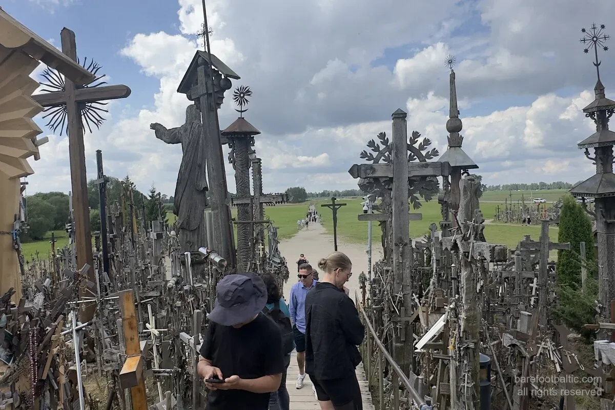 Collina delle Croci, Lituania, la passerella d’accesso con la statua di Gesù pellegrino e le croci intagliate a mano.