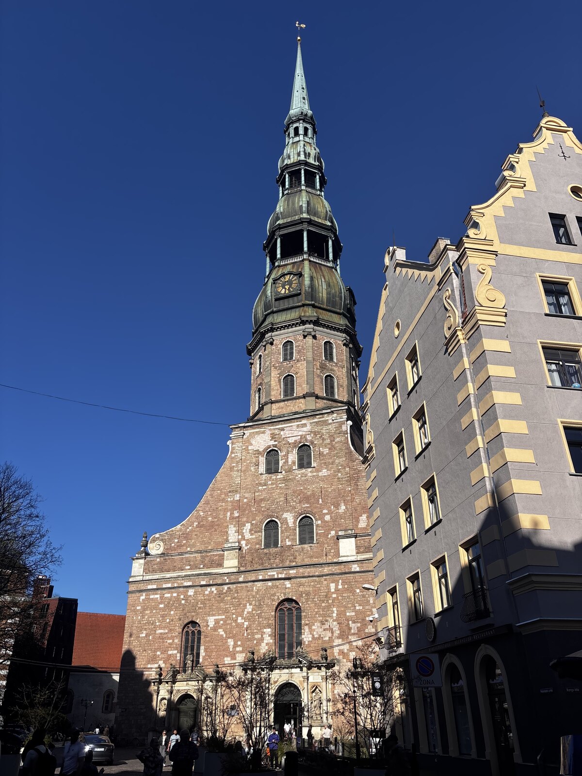 La Chiesa di San Pietro (Sv. Pētera baznīca) con la sua alta guglia verde contro un cielo azzurro nella Città Vecchia di Riga, Lettonia.