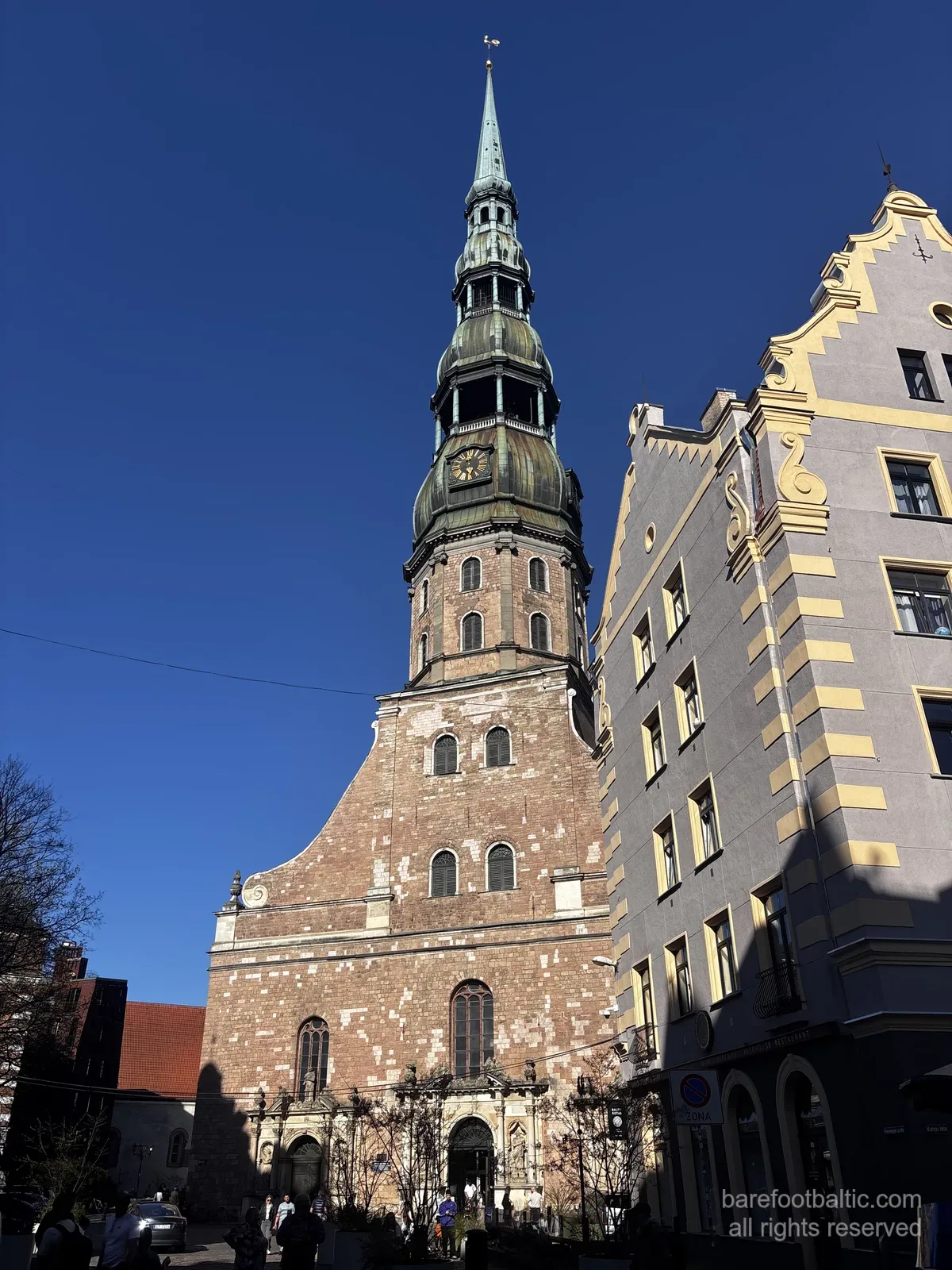 La Chiesa di San Pietro (Sv. Pētera baznīca) con la sua alta guglia verde contro un cielo azzurro nella Città Vecchia di Riga, Lettonia.