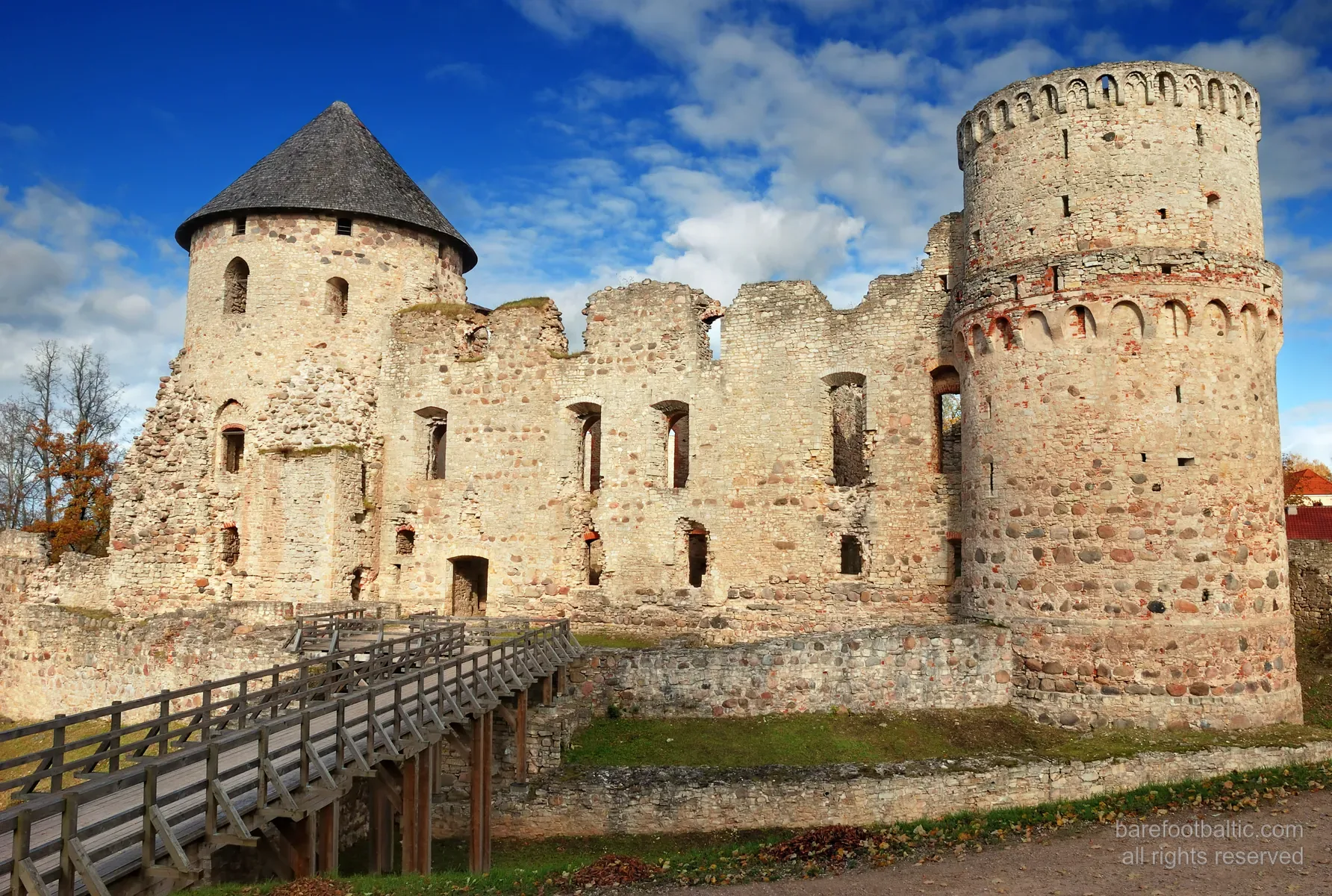 Esterno delle rovine del castello medievale di Cēsis, mura di mattoni rossi nella luce autunnale, Lettonia