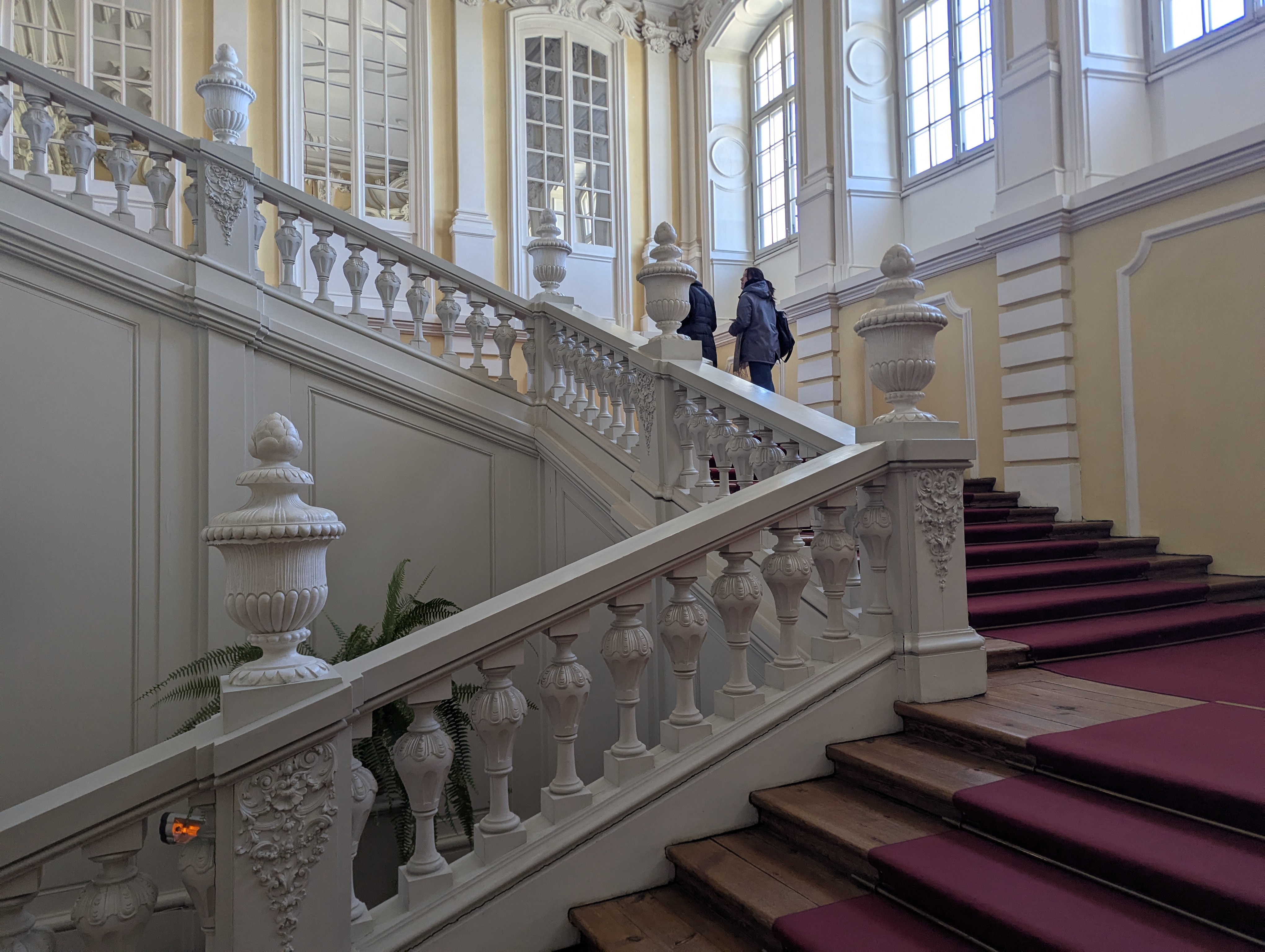 Scalone d&rsquo;onore del Palazzo di Rundāle con balaustre di stucco bianco e tappeto granata
