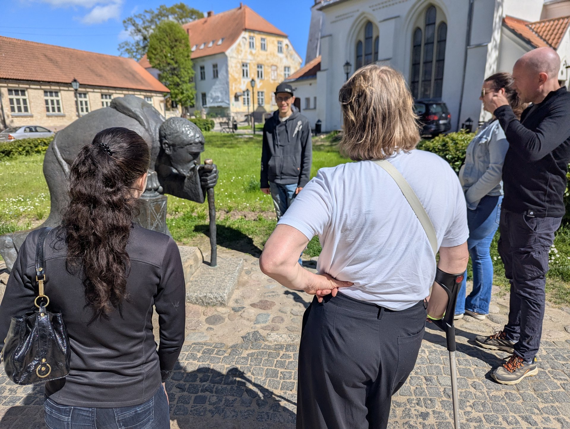Gruppo intorno alla scultura di bronzo del pellegrino nel centro storico di Cēsis