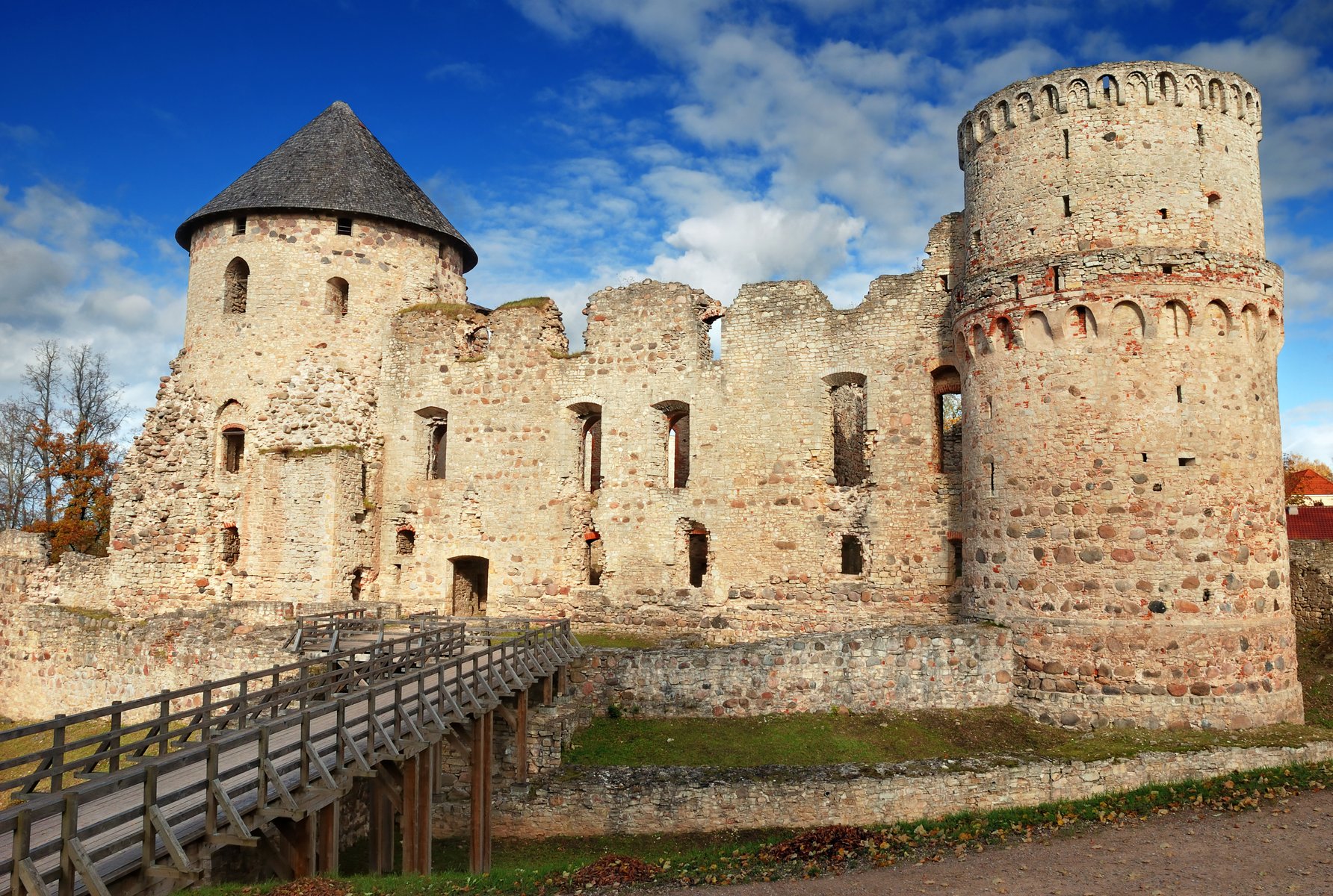 Le torri dalle mura rosse del castello di Cēsis sotto un cielo azzurro