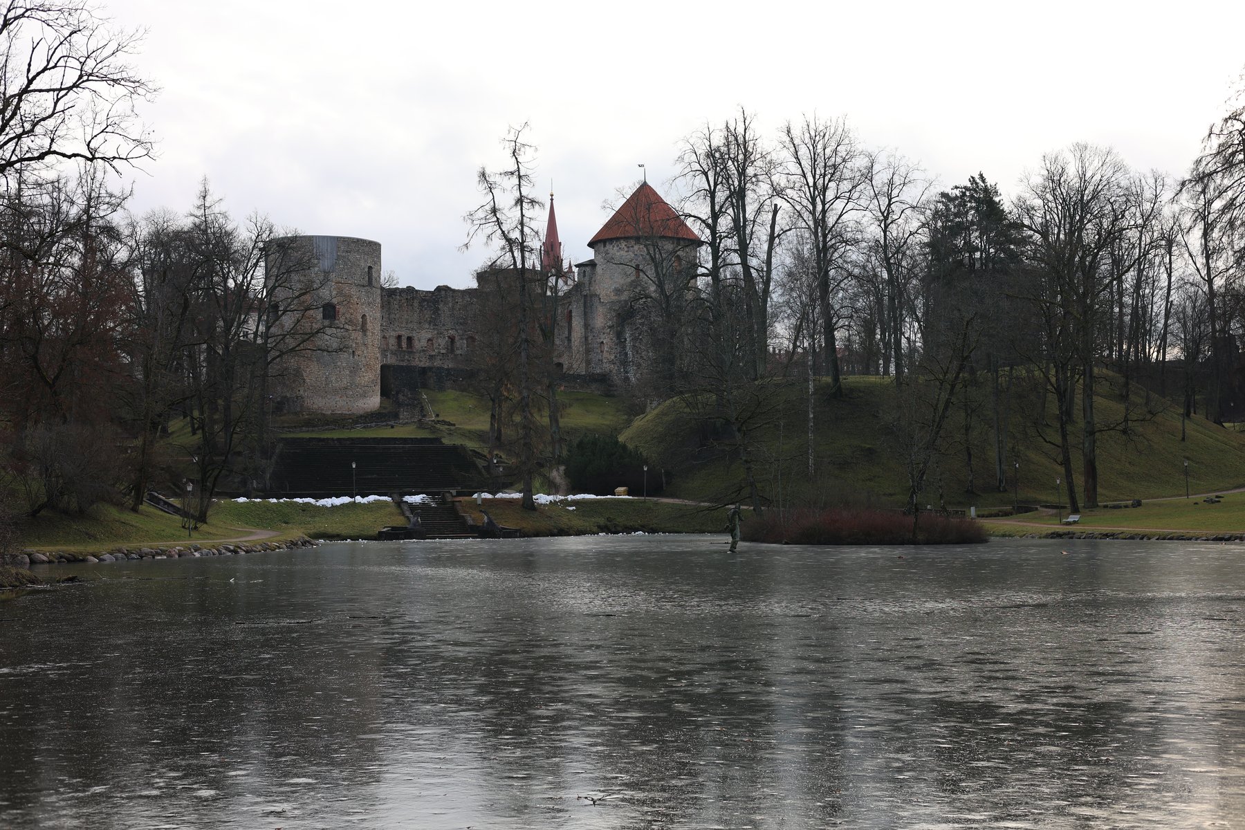 Castello di Cēsis riflesso in uno stagno invernale con alberi spogli