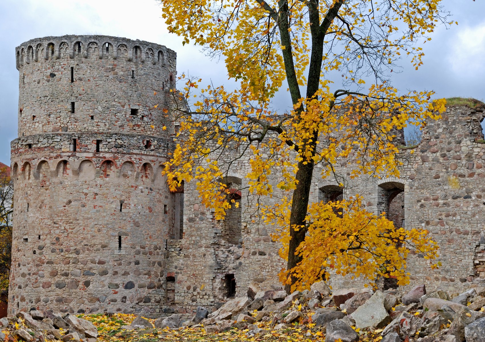 Mura di pietra del castello di Cēsis incorniciate da foglie dorate d'autunno