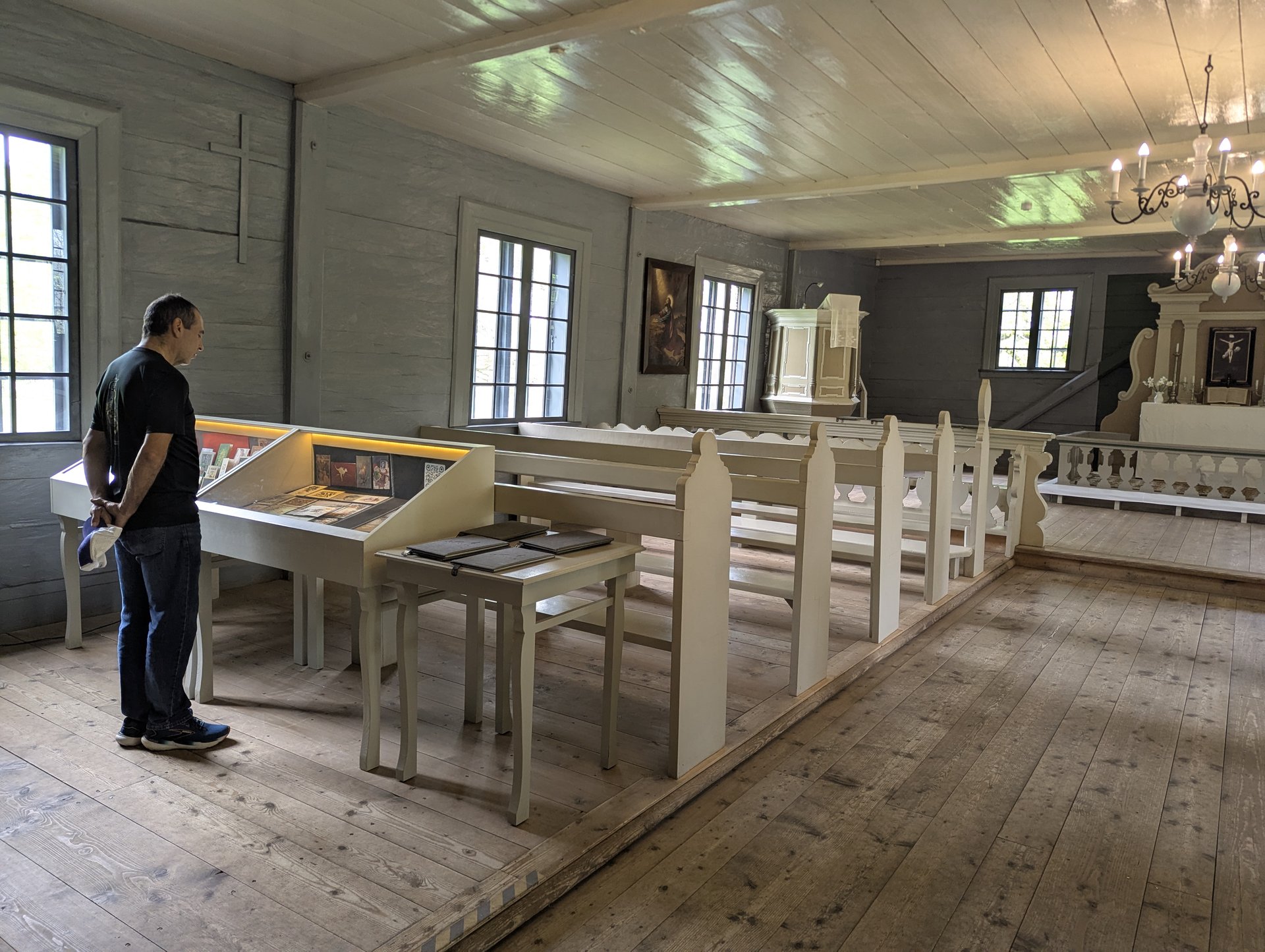 Interno del museo-chiesa di legno di Vidzeme con un visitatore davanti alle vetrine