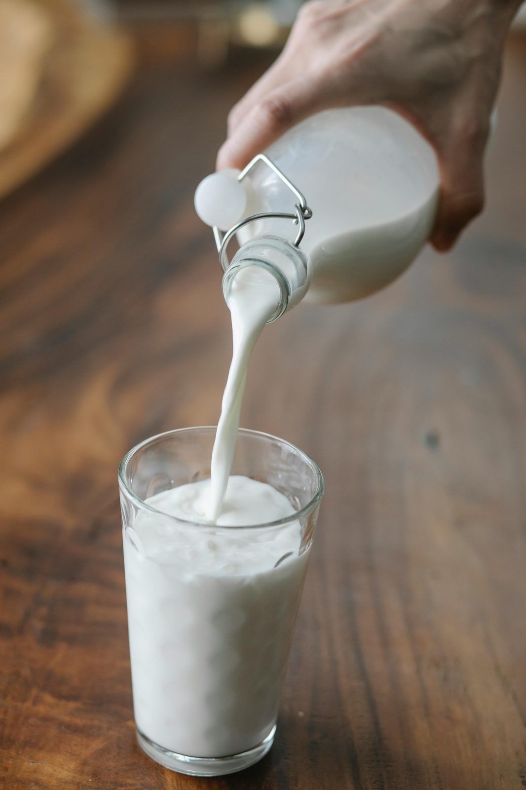 Kefir lettone versato da una bottiglia in un bicchiere su un tavolo di legno