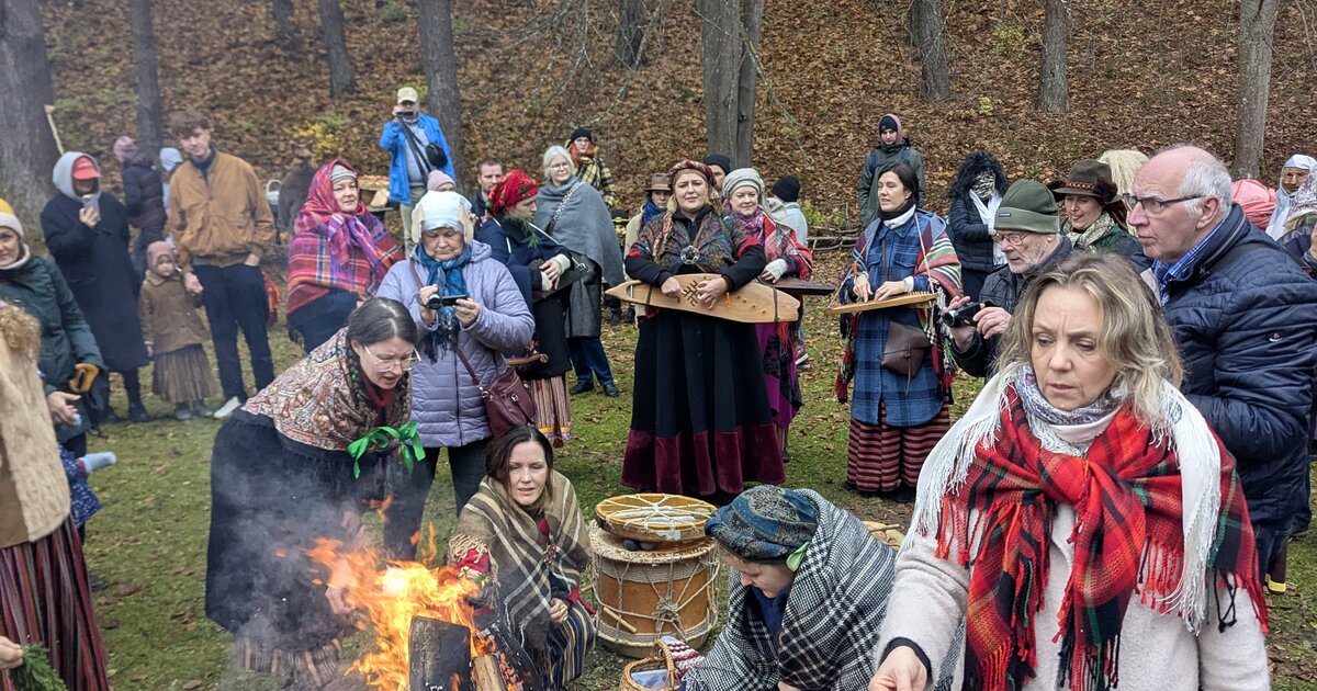 Visitatori in costume popolare attorno a un falò di Mārtiņdiena al Museo Etnografico all’Aperto della Lettonia, Riga.